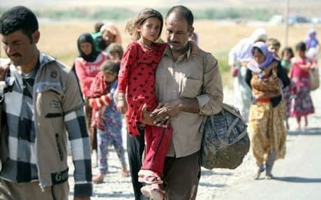 A Yezidi man carries his child as they flee ISIS on August 11, 2014. Photo: Ahmad al-Rubaye/AFP