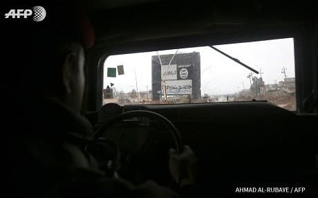 Iraqi forces pass an ISIS billboard in Arabi district, north Mosul. Photo: Ahmad al-Rubaye/AFP
