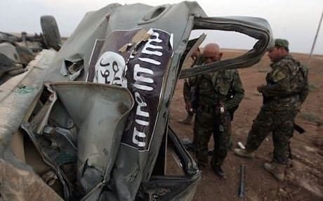 Kurdish Peshmerga fighters inspect an ISIS vehicle destroyed by a US airstrike. Photo: AFP/file