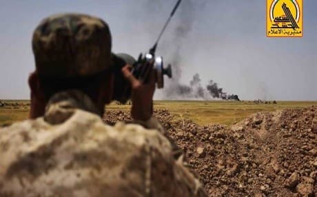 A Hashd al-Shaabi fighter peers at a distant strike in northern Iraq. Photo: Iraqi PMU