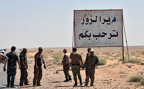 Syrian troops and pro-regime allies stand near a sign that reads ‘Deir er-Zor welcomes you.’ Photo: SANA via AP