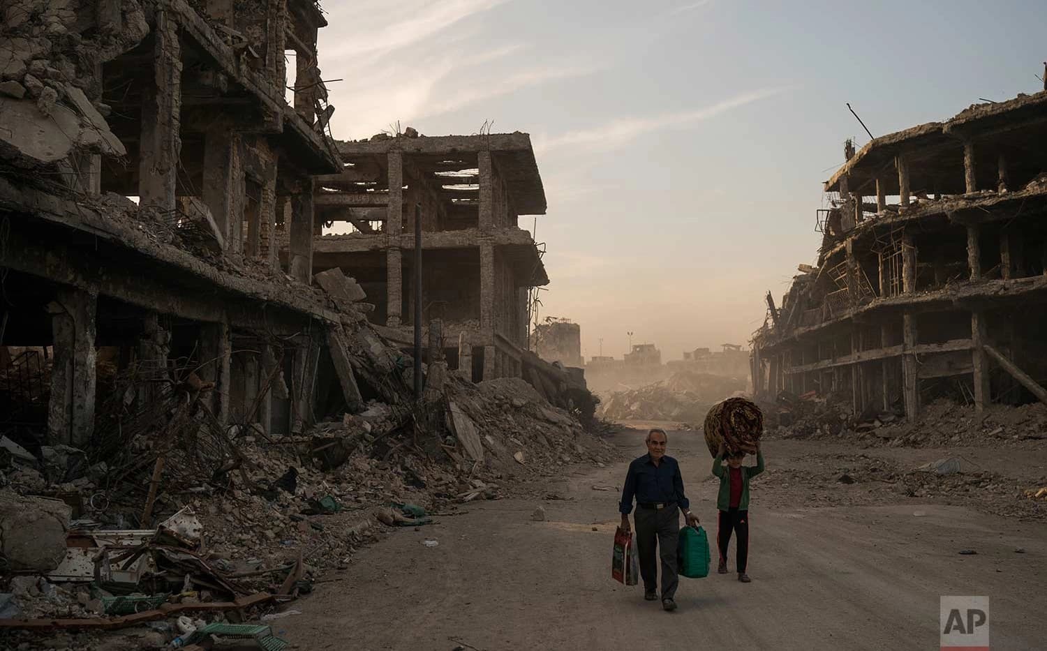 Two Mosul residents carry belongings from their home to wash before returning to live in Mosul’s Old City neighbourhood in November. Photo: Felipe Dana/AP