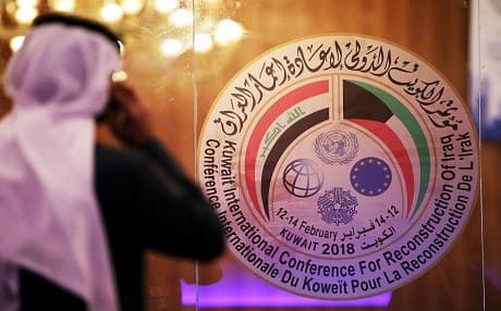 A Kuwaiti journalist speaks on his phone in front of the logo of the Iraq reconstruction conference, at the media centre in Kuwait City on February 11, 2018. Photo:AFP/Yasser Al-Zayyat