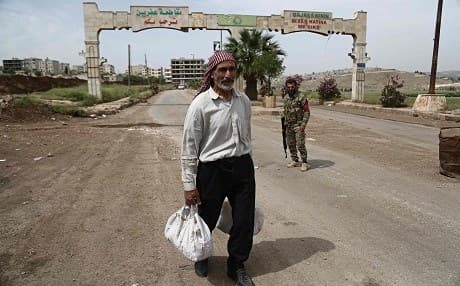 A man walks past armed guards at the gates of Afrin last month. Photo: Nazeer al-Khatib/AFP