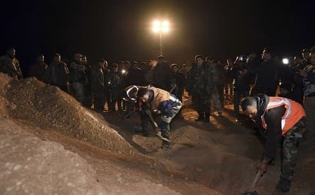 This imaged released in December 2017, a Syrian security force member checks human remains at the site where two mass graves were discovered. File photo: SANA