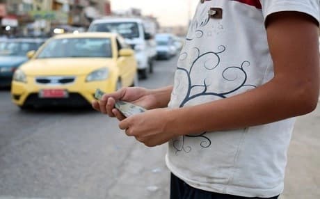 An Iraqi child peddlar holds 250 Iraqi dinar banknotes standing along a a street in Mosul, Iraq, on July 7, 2018. Photo: Waleed al-Khalid