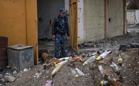 A member of Iraq's federal police stands in front of explosives in Mosul. Photo: AP