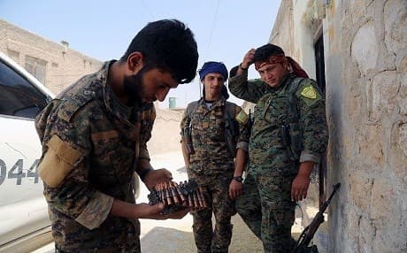 Members of the SDF stand on a street in the northern Syrian city of Manbij on August 7, 2016, as they comb the city in search of the last remaining jihadists, a day after they retook it from ISIS. Photo: Delil Souleiman | AFP