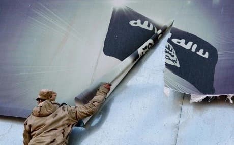 An Iraqi soldier tears down an ISIS flag in Mosul after the city's liberation. File photo: Mahmud Saleh/AFP