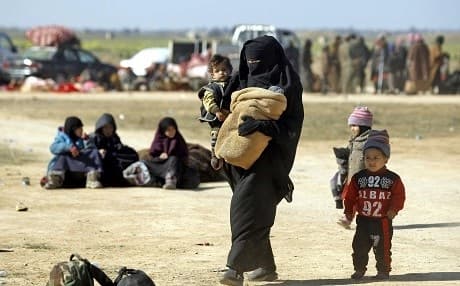 A Syrian woman walks carrying a child with other children as they flee the battered Islamic State-held holdout of Baghouz on February 12, 2019. Photo: Delil Souleiman/AFP