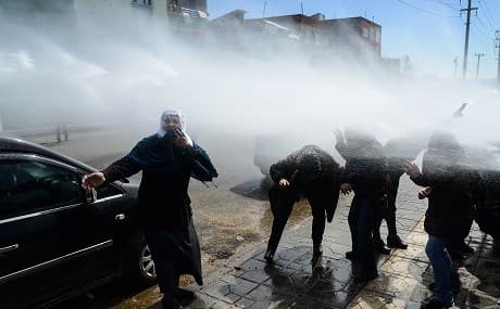 Protestors sing victory as Turkish anti-riot police officers use water cannon during the funeral of Kurdish activist Zulkuf Gezen in the Turkish city of Diyarbakir, March 18, 2019. Photo: Ilyas Akengin / AFP