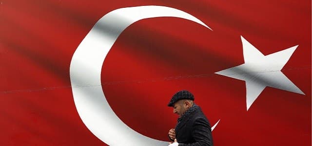 A man walks by a giant Turkish flag in Ankara, Turkey, March 31, 2019. Photo: Ali Unal / AP