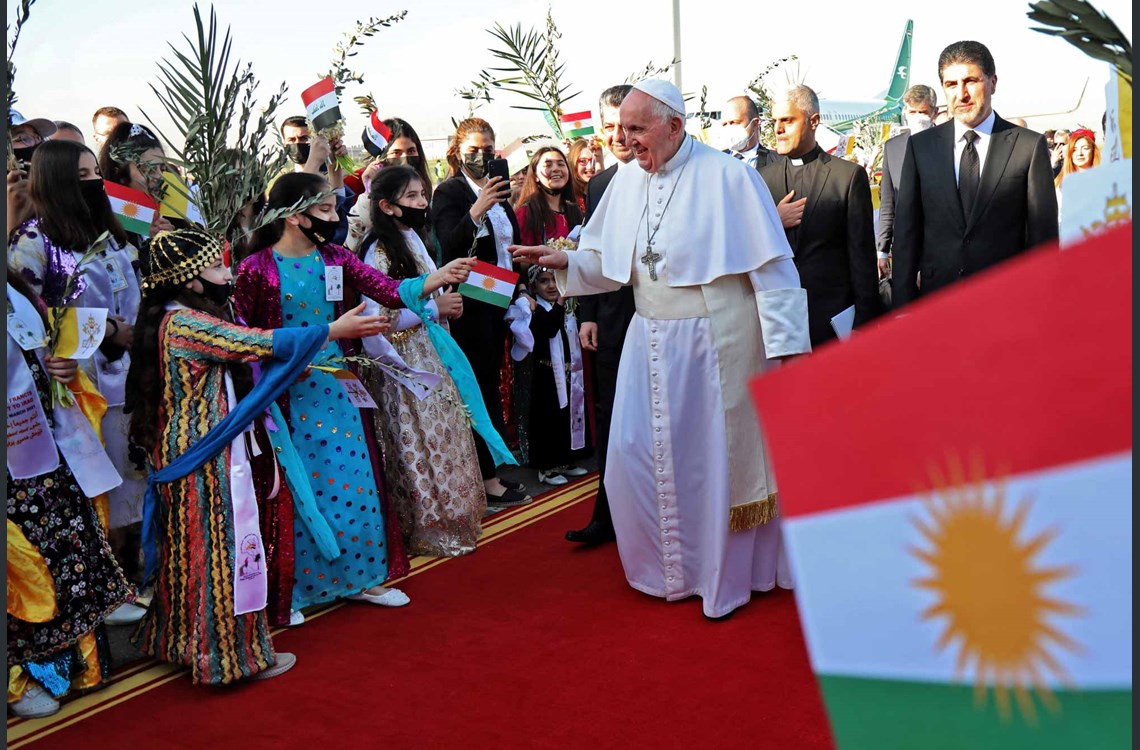 Pope Francis (C), accompanied by the President of the Kurdistan Region Nechirvan Barzani (R), greets people dressed in traditional outfits upon his arrival at Erbil airport on March 7, 2021, in the capital of the autonomous region. Photo: Safin HAMED / AFP