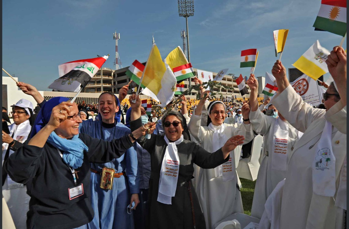  Nuns wave flags of Iraq, Kurdistan, and the Holy See as they wait for the arrival of Pope Francis at the Franso Hariri Stadium in Erbil, on March 7, 2021, in the capital of the Kurdistan Region. Photo by Safin Hamed / AFP