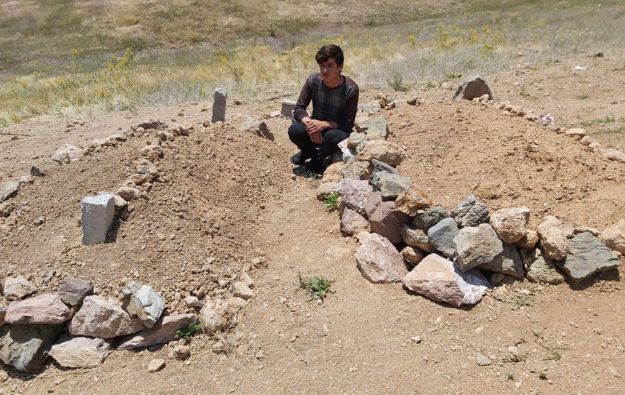 Ozal, the 18-year-old brother of Arsalan and Shamzin, sits beside their graves. Photo: Jabar Dastbaz / Rudaw