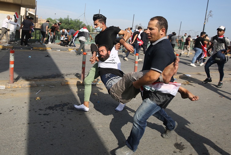 Iraqi protesters carry a comrade who fainted due to tear gas used by security forces to disperse the crowds in central Baghdad, October 25, 2019. Photo: AFP