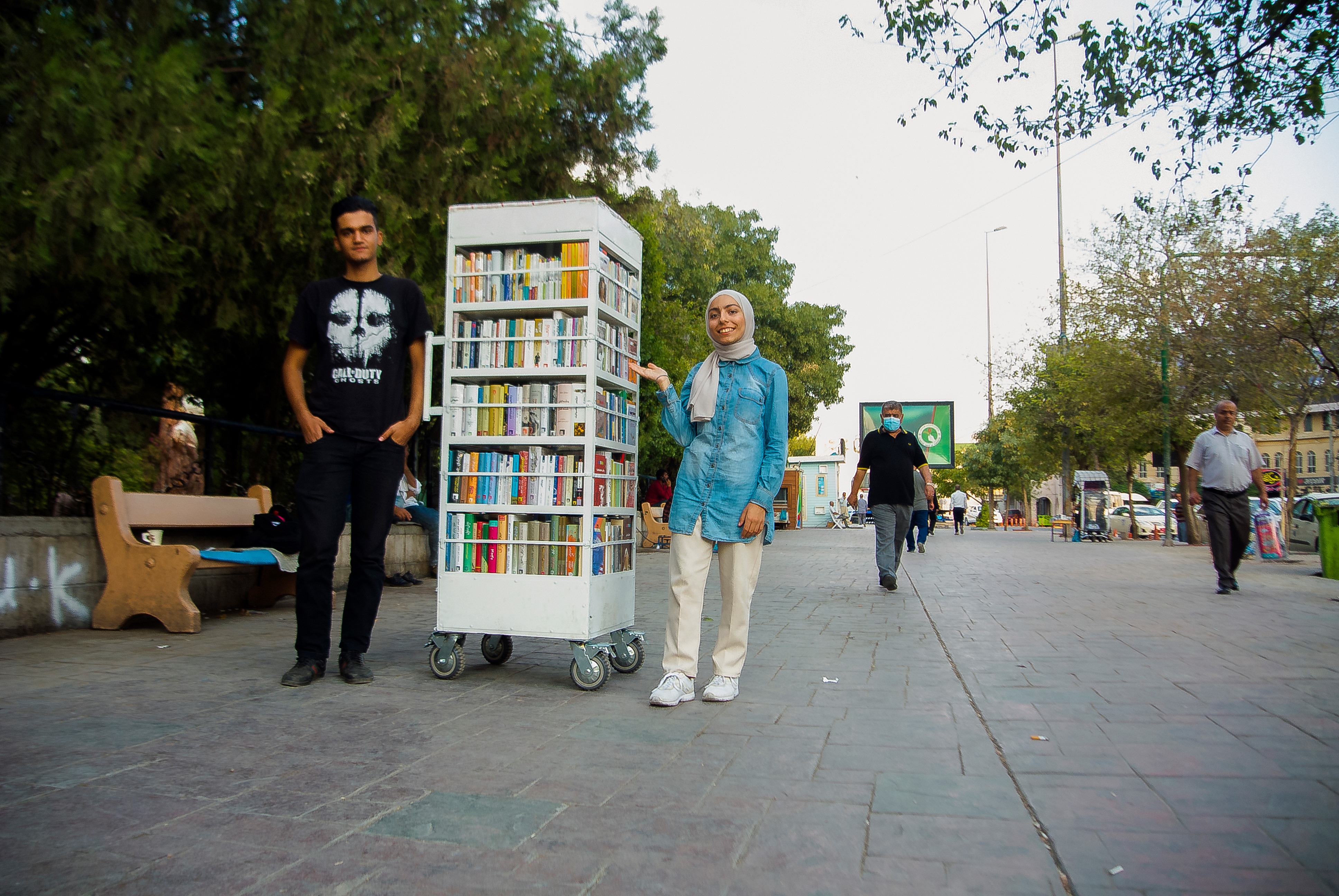 چراخان تۆفیق و زامۆ عومەر لە تەنیشت کتێبفرۆشییە بچووکەکەیان. وێنە؛ زمناکۆ ئیسماعیل