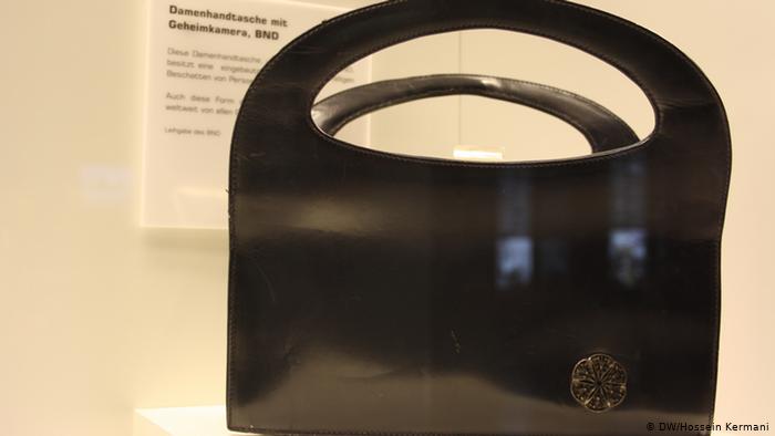 جانتایه‌كى ده‌ستى ژنانه‌. كامێرایه‌كى زۆر بچووك له‌ نێوه‌ڕاستى لۆگۆى ئه‌م جانتایه‌ هه‌یه‌ ، ئه‌م جانتایه‌ له‌لایه‌ن ده‌زگاى هه‌واڵگریى ئه‌ڵمانیا (BND ) دروستكراوه‌.