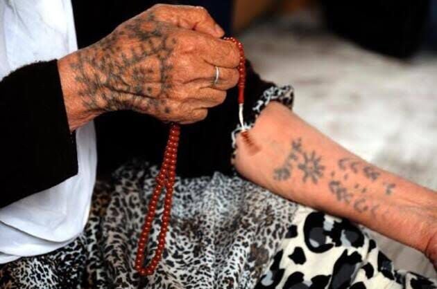 Sağ elde Güneş ve muhtemelen Ayna. Sol kolda içinde Güneş ve Başak sembolü