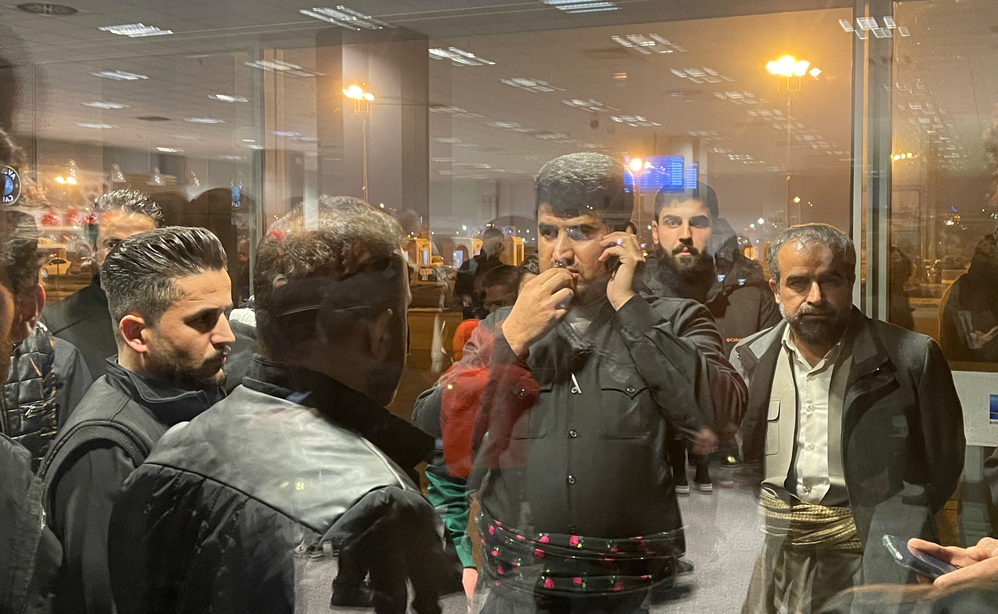 Zana Mamand, whose brother Twana is assumed to have drowned in the dinghy and whose body is yet to be found, speaks on the phone as he awaits the return of the 16 recovered bodies on December 26, 2021. Photo: Bilind T. Abdullah / Rudaw