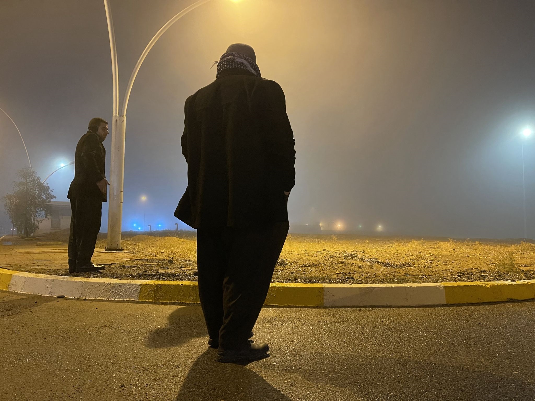 Family members stand in the mist as they wait for the plane carrying the corpses of their loved ones to land, before discovering the flight had been postponed, on December 24, 2021. Photo: Fazel Hawramy / Rudaw