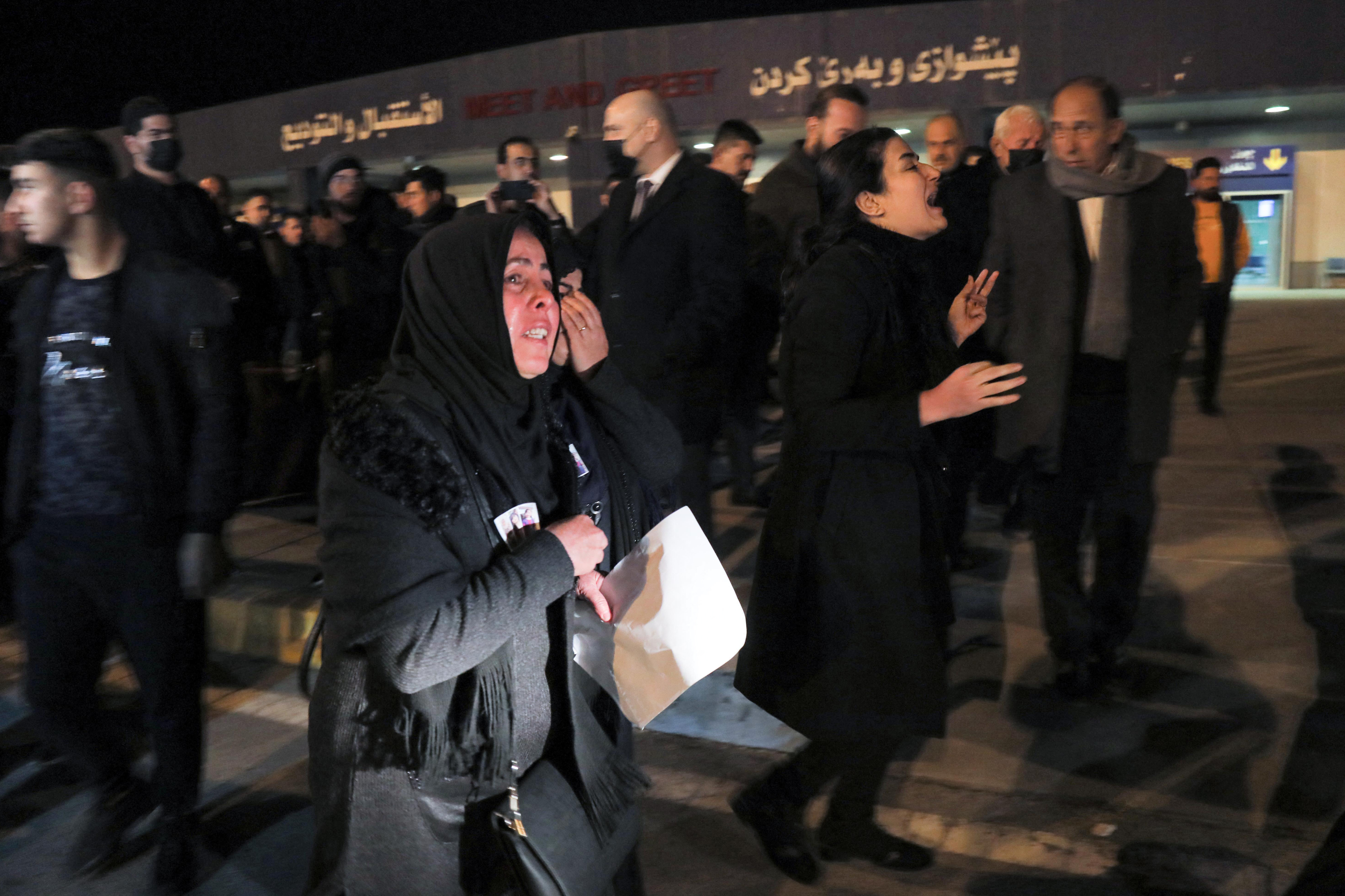 Relatives mourn as they await the arrival of the bodies of five Kurdish migrants who died a month prior as their boat capsized while attempting a crossing of the Aegean Sea, at Erbil airport on February 1, 2022. Safin Hamed/AFP