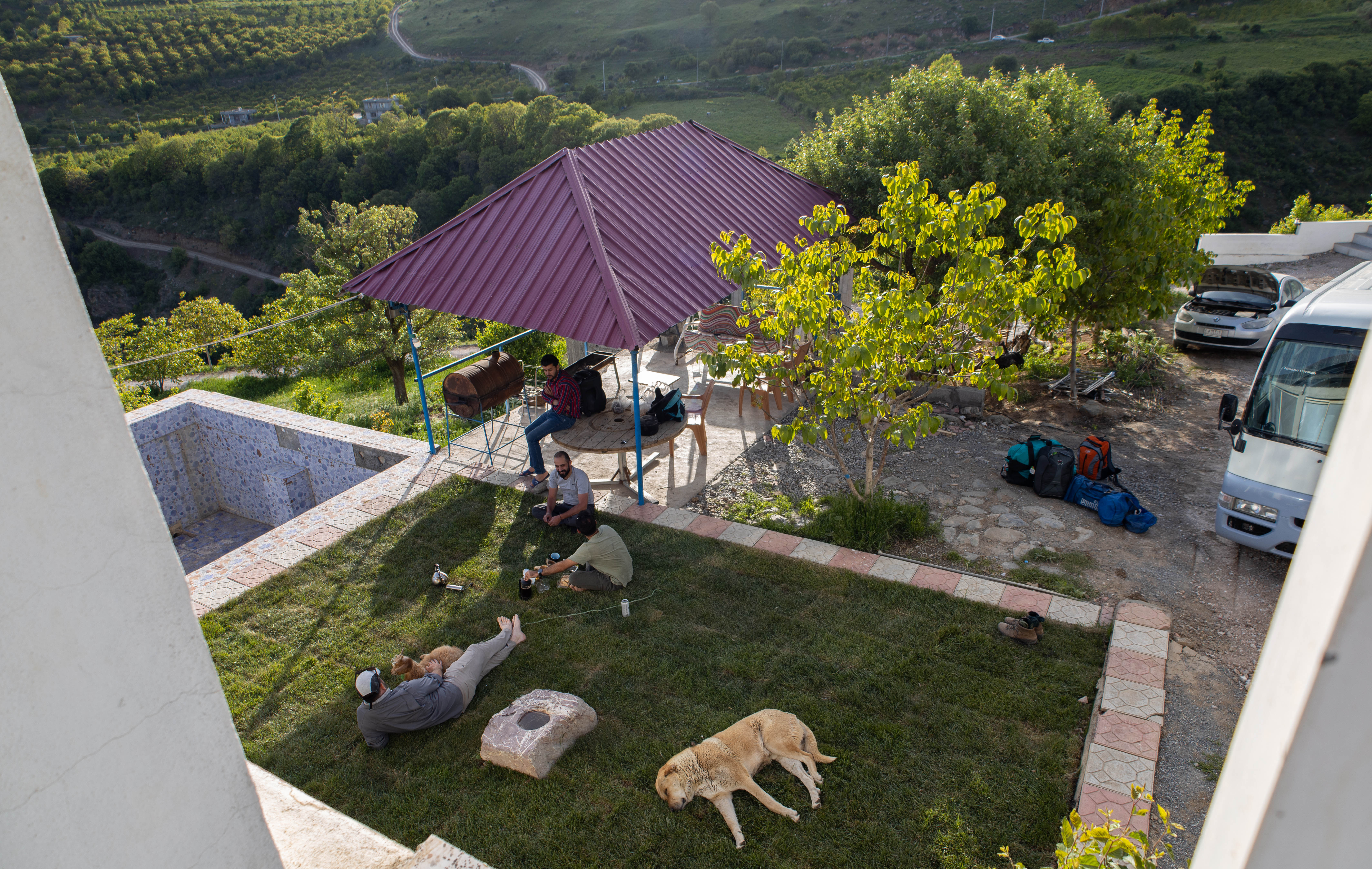 Members of the team, plus dog and goat, relax in the grounds of Omer Chomani’s Choman mountain lodge, on May 14, 2022. Photo: Alannah Travers/Rudaw