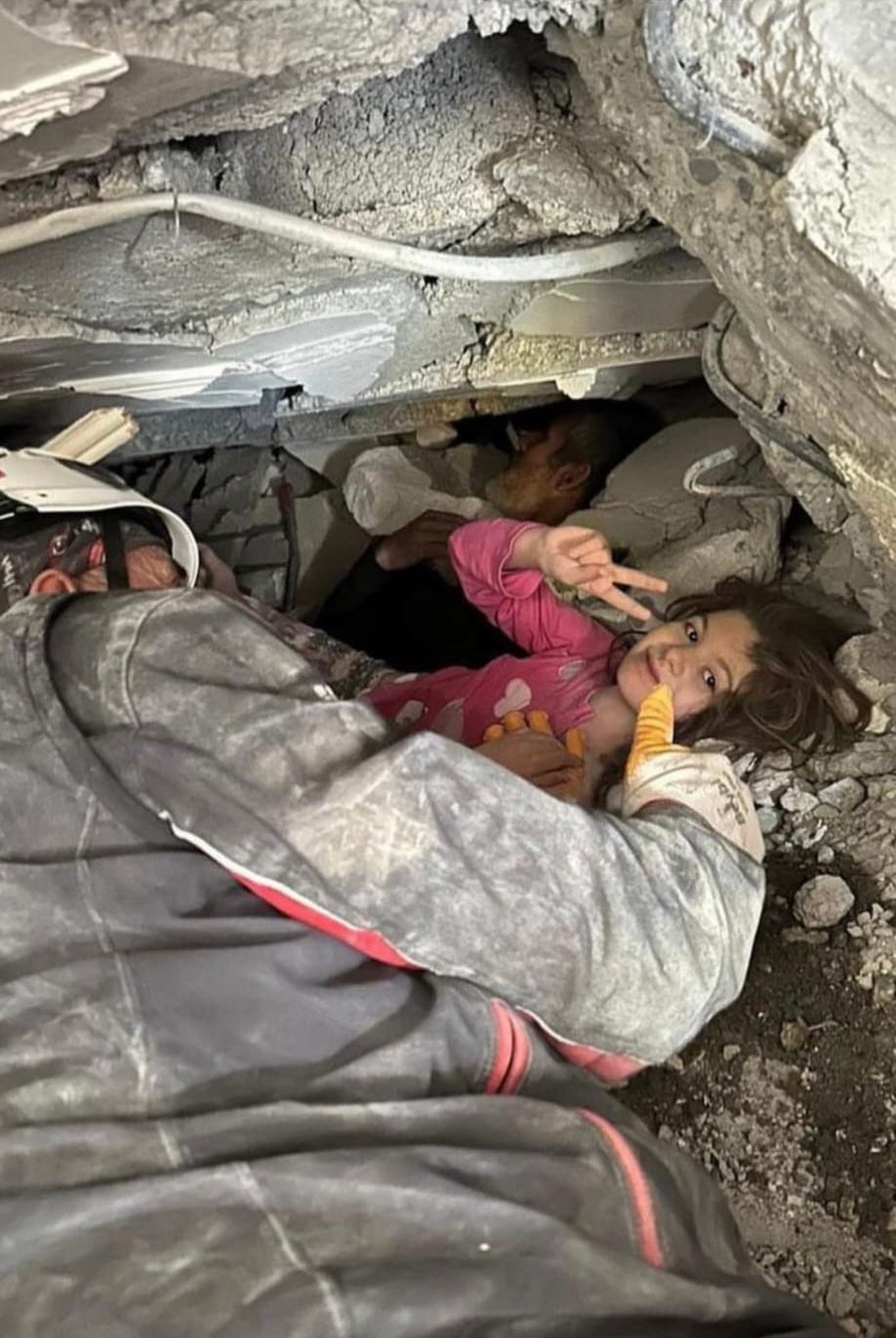 Enkazdan kurtarılırken zafer işareti yapan bir çocuk