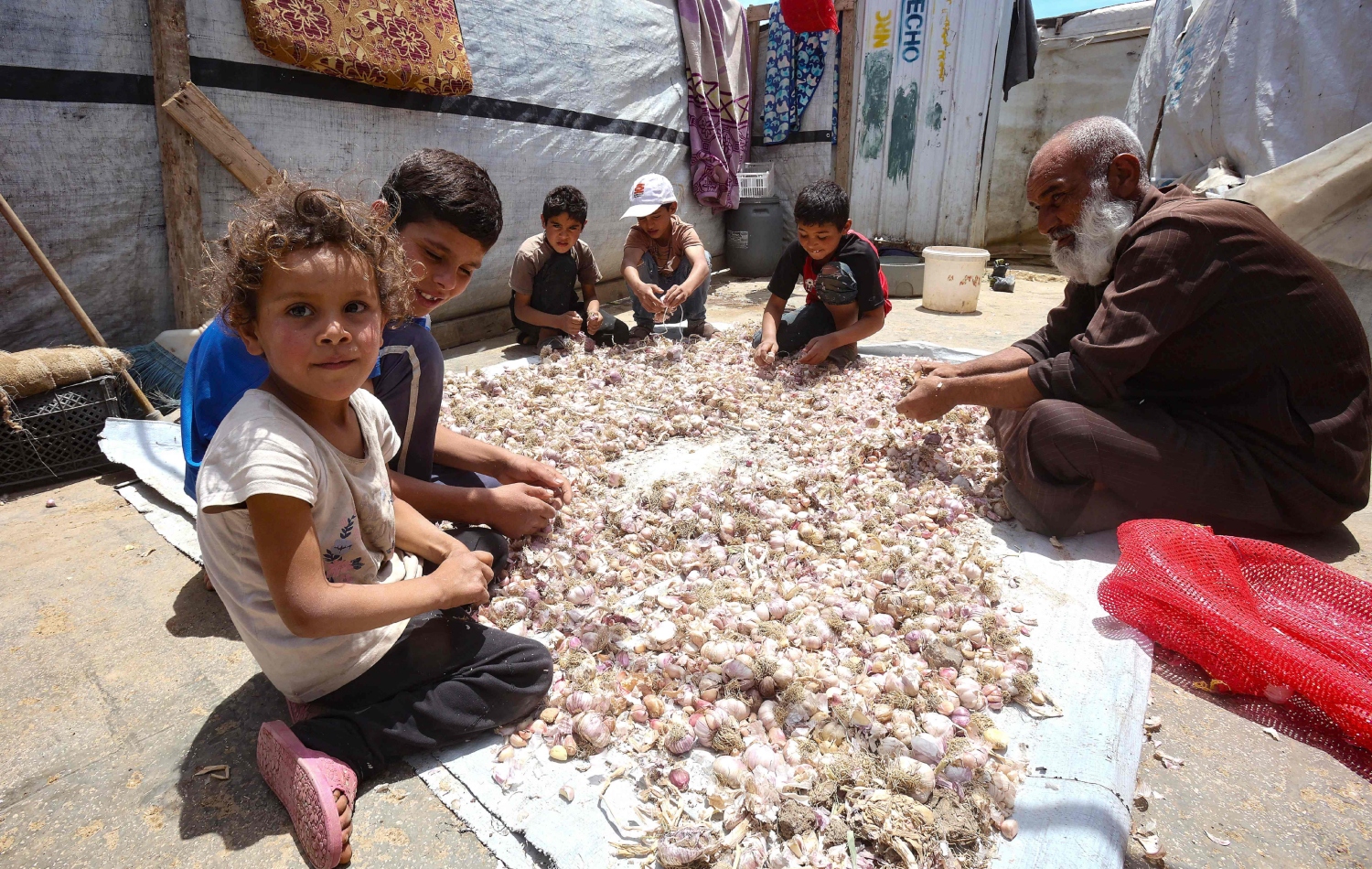 ئیبراهیم قورباوی تەمەن 48 ساڵ لەکاتی پاککردنی سیردا لەگەڵ منداڵەکانی لەبەردەم خێوەتەکەیان لە کامپی سەعەدنایل، وێنە: ANWAR AMRO / AFP