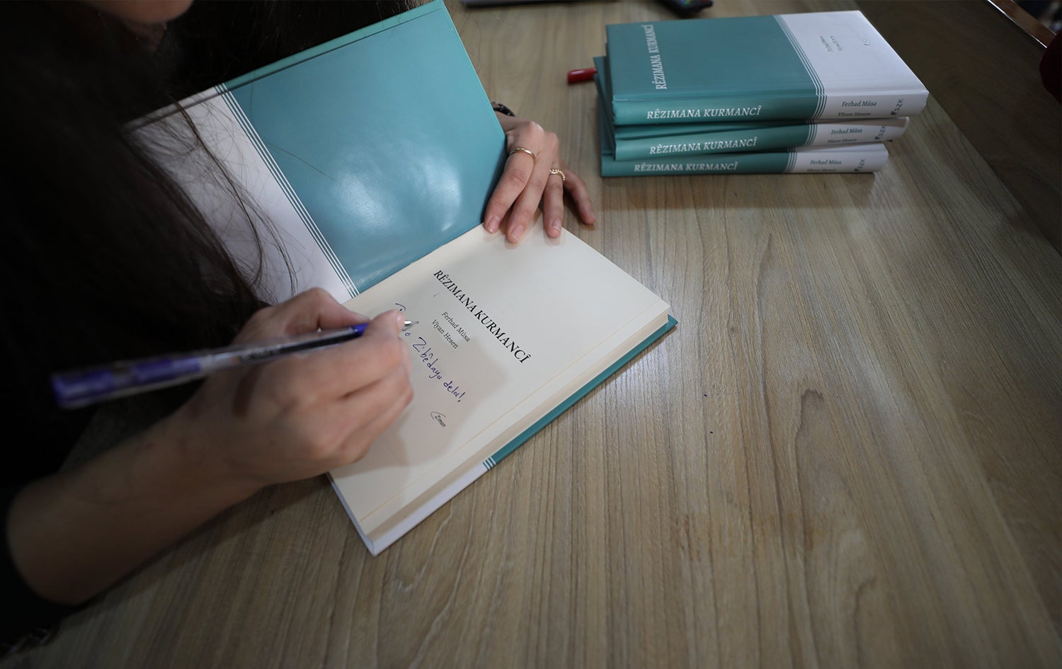 Viyan Hassan signs a copy of the Kurmanji Grammar book she co-wrote. Date: October 25, 2023. Photo: SZK