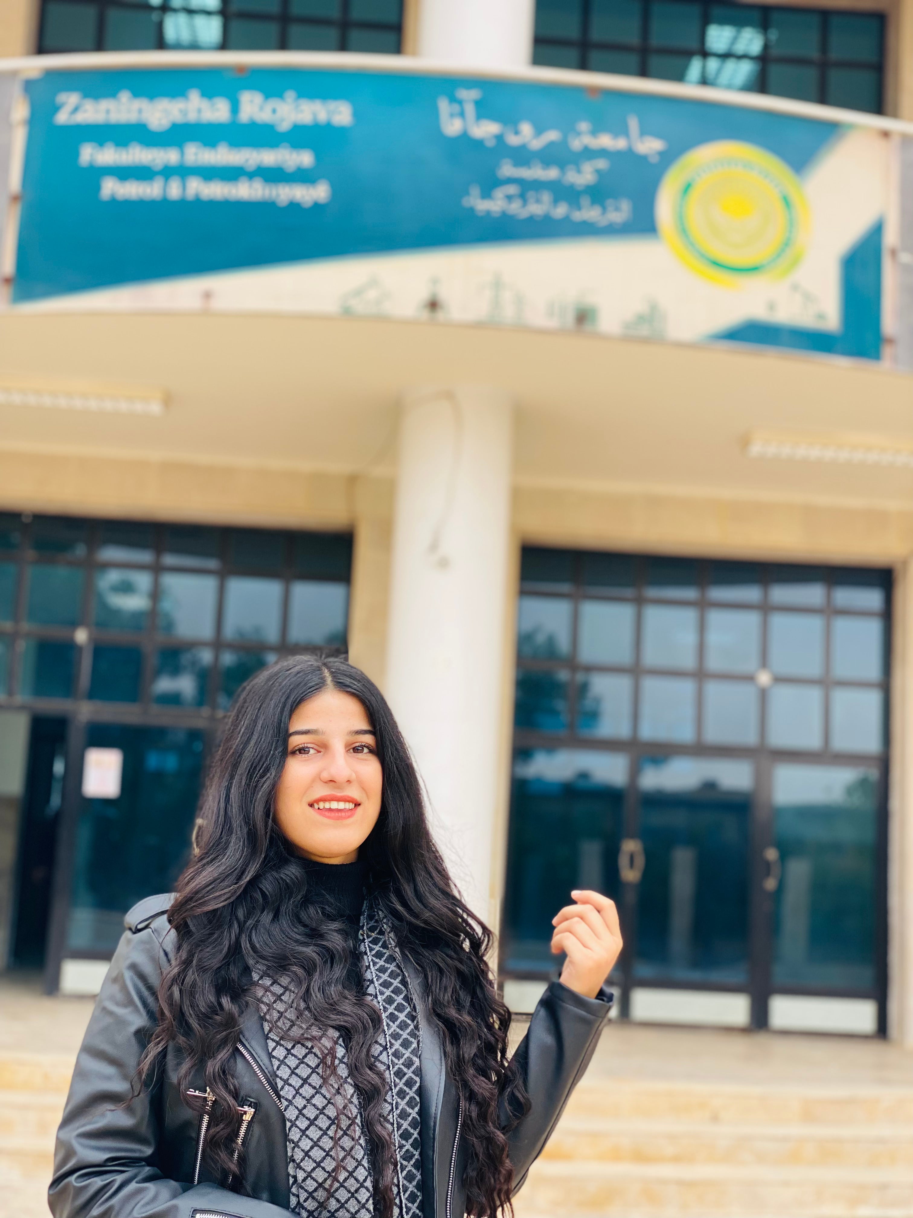 Lavin Batal, a student, poses for a photo in front of the University of Rojava’s faculty of Petrochemical and Chemical Engineering in Qamishli, northeast Syria (Rojava) on November 26, 2023. Photo: submitted