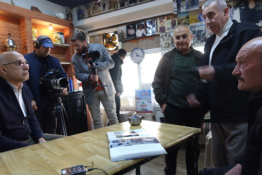 Çayxaneya ku ji nû ve hatiye avakirin. Ji çepê ber bi rastê: Sîrwan, derhêner; Dilşad, wênegir; Hute, şofêr û alîkarê wênegir û lawê xwediyê qehwexaneyê li milê rastê.