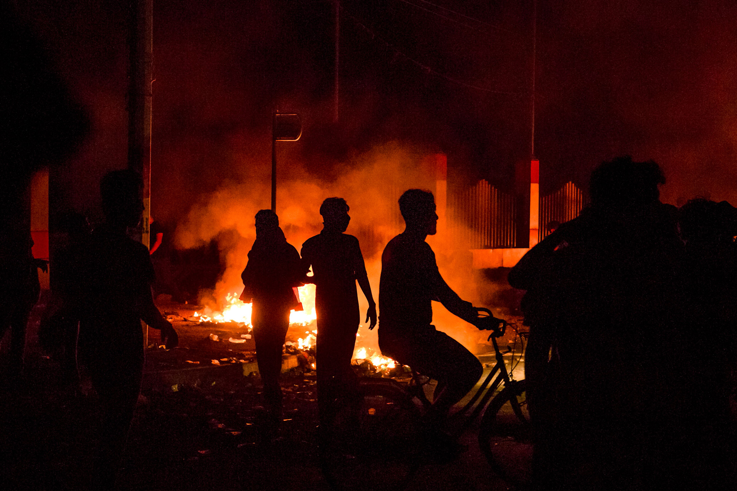 Iraqi protesters walk past fires in the street during an anti-government demonstration outside the local government headquarters in Basra. Photo: AFP