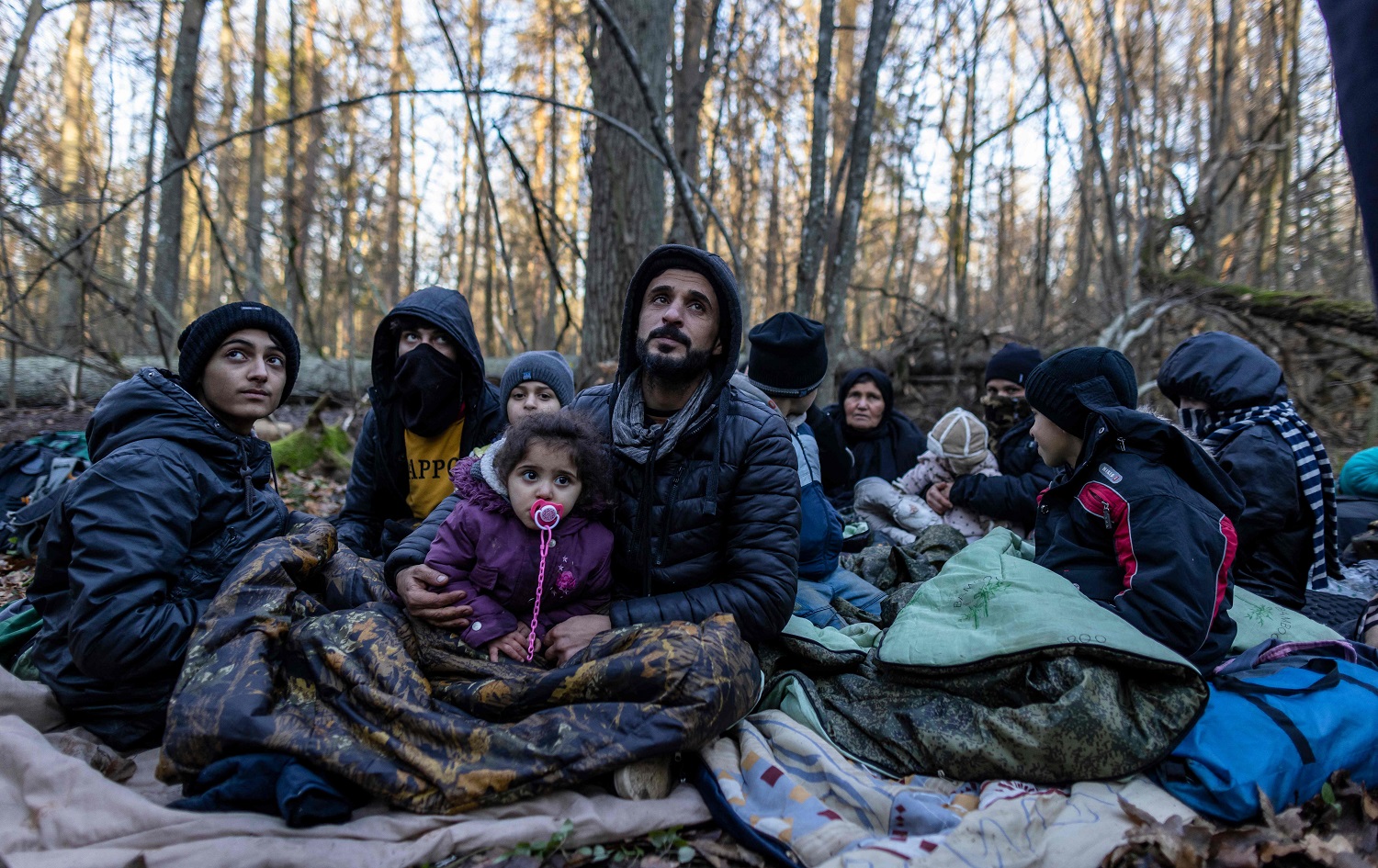 Members of a three-generation Kurdish family from Duhok are seen in a forest near the Polish-Belarus border while waiting for the border guard patrol, near Narewka, Poland, on November 9, 2021. Photo: Wojtek Radwanski/AFP