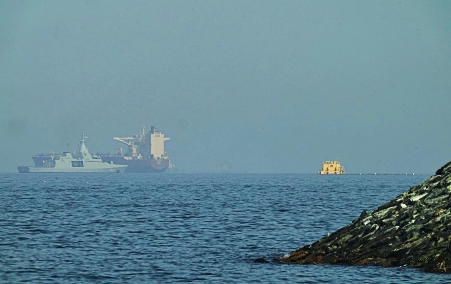 Foto: 1 Mayıs 2026'da Birleşik Arap Emirlikleri'nin Khor Fakkan kenti yakınlarındaki bir sahil yolundan çekilen bu karede, bir Emirlik devriye botu (solda), Hürmüz Boğazı yakınlarında Umman Körfezi'ne demirlemiş bir tankerin yanında görülüyor. (Fatima Shbair / Associated Press)