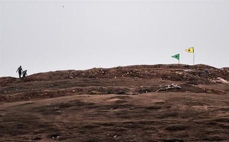Kurdish YPG forces plant their flag on a hill outside Kobani after expelling ISIS militants from the city. Photo: AFP