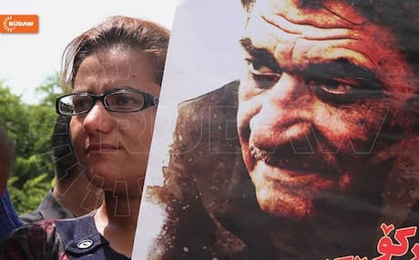 A mourner in Sulaimani holds a poster of Kurdish poet Sherko Bekas who passed away this month, aged 73. Photo: Rudaw