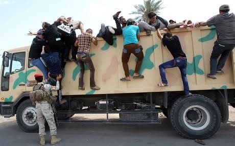  Iraqi Shiite volunteers jump on an army truck outside a recruitment center in Baghdad to join the fight against the Islamic State (ISIS). 2014. Photo: AFP