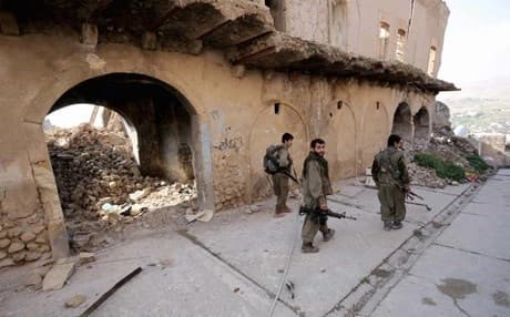 PKK fighters walk through the damaged town of Shingal. AP file photo