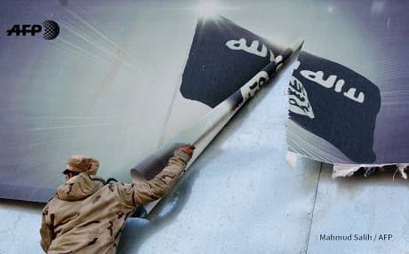 A member of the Iraqi security forces tears down an ISIS poster in east Mosul over the weekend. Photo: Mahmud Salih/AFP