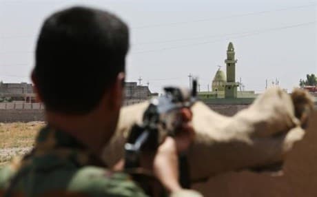 The ethnically diverse and disputed city of Tuz Khurmatu has seen clashes between Kurdish Peshmerga and Shiite Hashd al-Shaabi in the past. Here, a Peshmerga stands guard outside the town. Photo: Rudaw