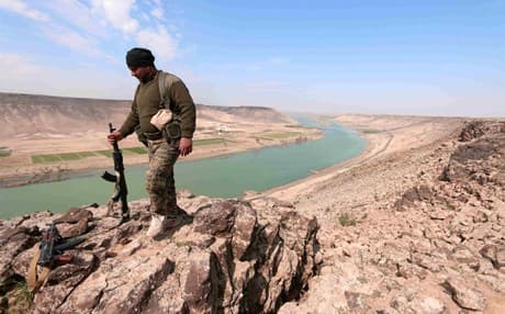 A fighter stands atop the Tabqa Dam in Syria. Photo: AFP