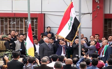 Kirkuk Governor Najmadin Karim raises the Iraqi flag to fly next to the Kurdish flag over a government building in the northern Iraqi city of Kirkuk. Photo: AFP/Mariwan Ibrahim 