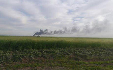 Buildings smolder in the distance in this unverified photo from northern Syria on Wednesday. Photo: YPG Press Office