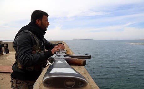 A Coalition-partnered anti-ISIS ground fighter looks over Tabqa Dam in northern Syria. Photo: Delil Souleiman | AFP