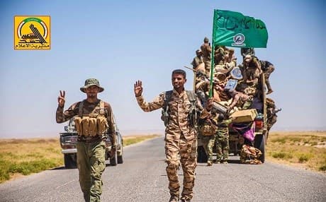 Members of the mainly Shiite Hashd al-Shaabi forces gesture as they drive against the ISIS positions near the Iraqi-Syrian border. Photo: Hashd media office. 