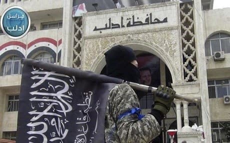 A member of Jabhat Fath al-Sham holds his group flag in front of Idlib province building. Photo: AP