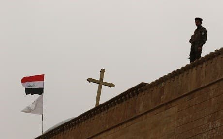 An Iraqi stands guard at the Saint John’s church in the Christian-Shabak contested town of Qaraqosh in Nineveh Province on December 25, 2016. Photo: Safin Hamed | AFP