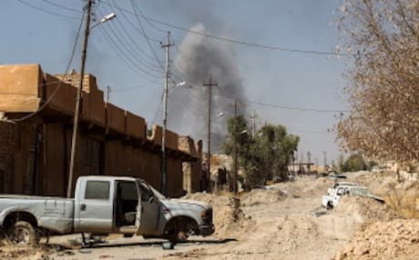 Smoke billows in the background past damaged vehicles as Iraqi forces, backed by the Hashd al-Shaabi units, advance inside the town of Tal Afar, west of Mosul. Photo: Ahmed Al-Rubaye/AFP