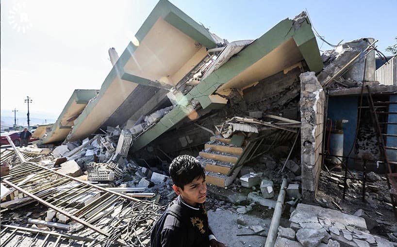 A boy walks past a building in Darbandikhan that was levelled in Sunday’s earthquake. Photo: Sartip Othman/Rudaw